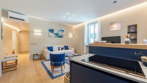 A modern kitchen with a built-in stove, a dining area with a bench, and a living space with a sofa and a coffee table. - A dreamlike apt in Piazzetta Portofino (Portofino)