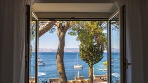 A view from a room with a large window overlooking a pool area with a clear blue sea and boats. - Dream property right on the water (Rogač)