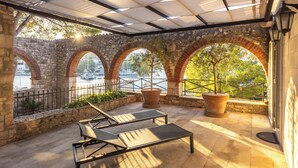 A covered outdoor area with stone arches, lounge chairs, and potted plants. - Dream property right on the water (Rogač)
