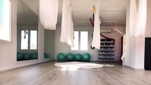 A spacious room with a wooden floor, green exercise balls, and white hanging fabric structures.