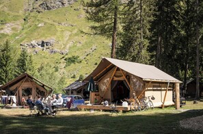 Ein Campingplatz mit zwei Holzhütten, einem Essbereich und Fahrrädern.