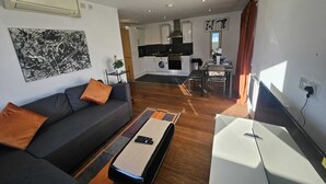 Ein modernes Wohnzimmer mit einer Couch, einem Couchtisch und einer Essecke mit Tisch und Stühlen.