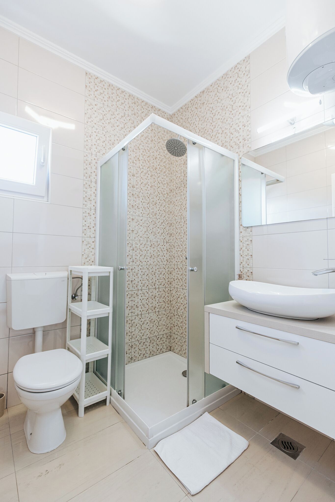 Une salle de bain moderne avec une douche à parois de verre, des toilettes blanches, un lavabo et un miroir.