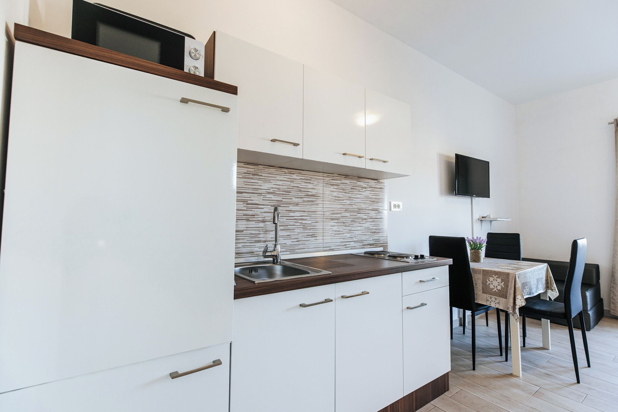 A modern kitchen with white cabinets, a wooden countertop, and a built-in microwave.