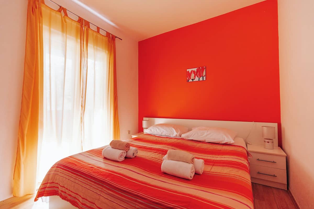 A hotel room with a bed, a nightstand, and a painting on the wall.