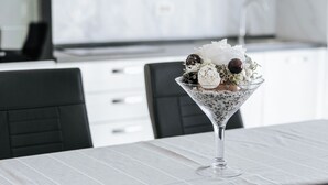 A martini glass with a dessert on a table in a modern kitchen with white cabinets and a tiled backsplash. - Apartments Lola (Novalja)