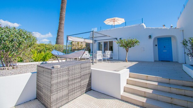 Eine moderne Außenpatio mit einer Sitzgruppe aus Rattangeflecht, einer blauen Tür und einer Palme.