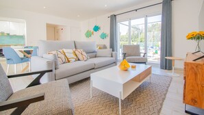 Ein modernes Wohnzimmer mit grauem Sofa, weißem Couchtisch und blauen Sesseln.