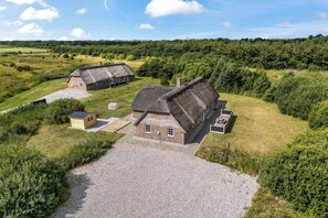 A rural property with two thatched-roof cottages, a gravel driveway, and surrounding greenery. - Large 16-person holiday home with pool, hot tub and sauna (Ulfborg)