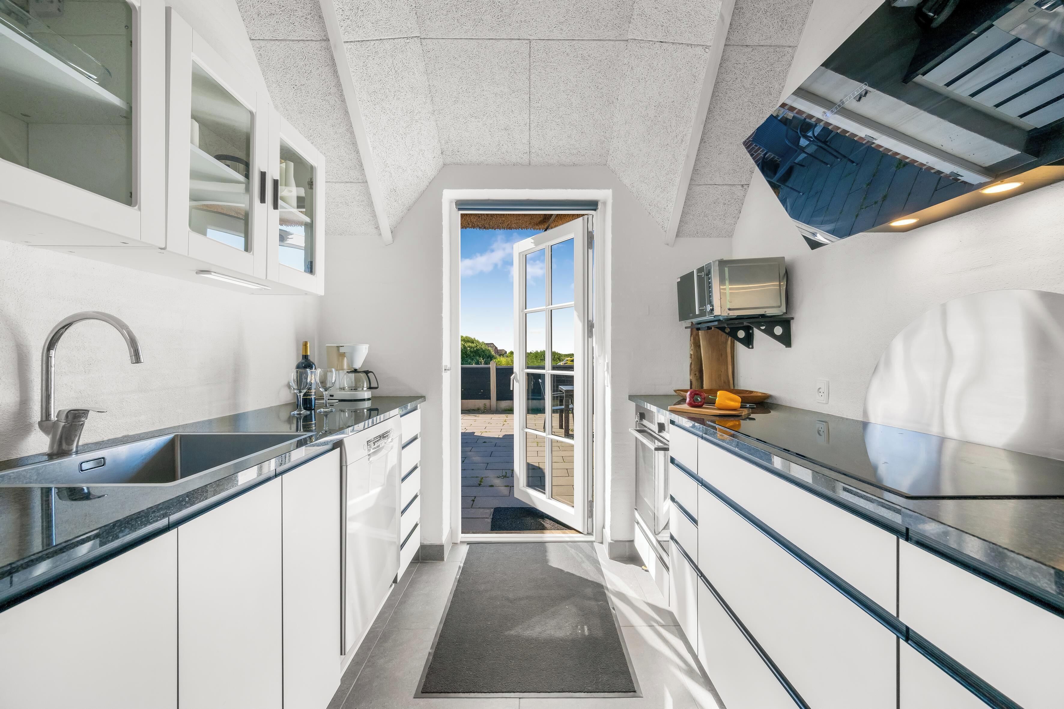 A modern kitchen with white cabinets, a built-in oven, and a large window.
