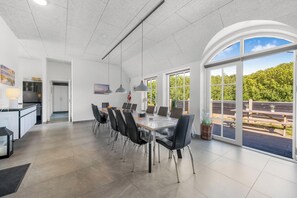 A modern kitchen with white cabinets and a dining area with a large table and chairs. - Large 16-person holiday home with pool, hot tub and sauna (Ulfborg)