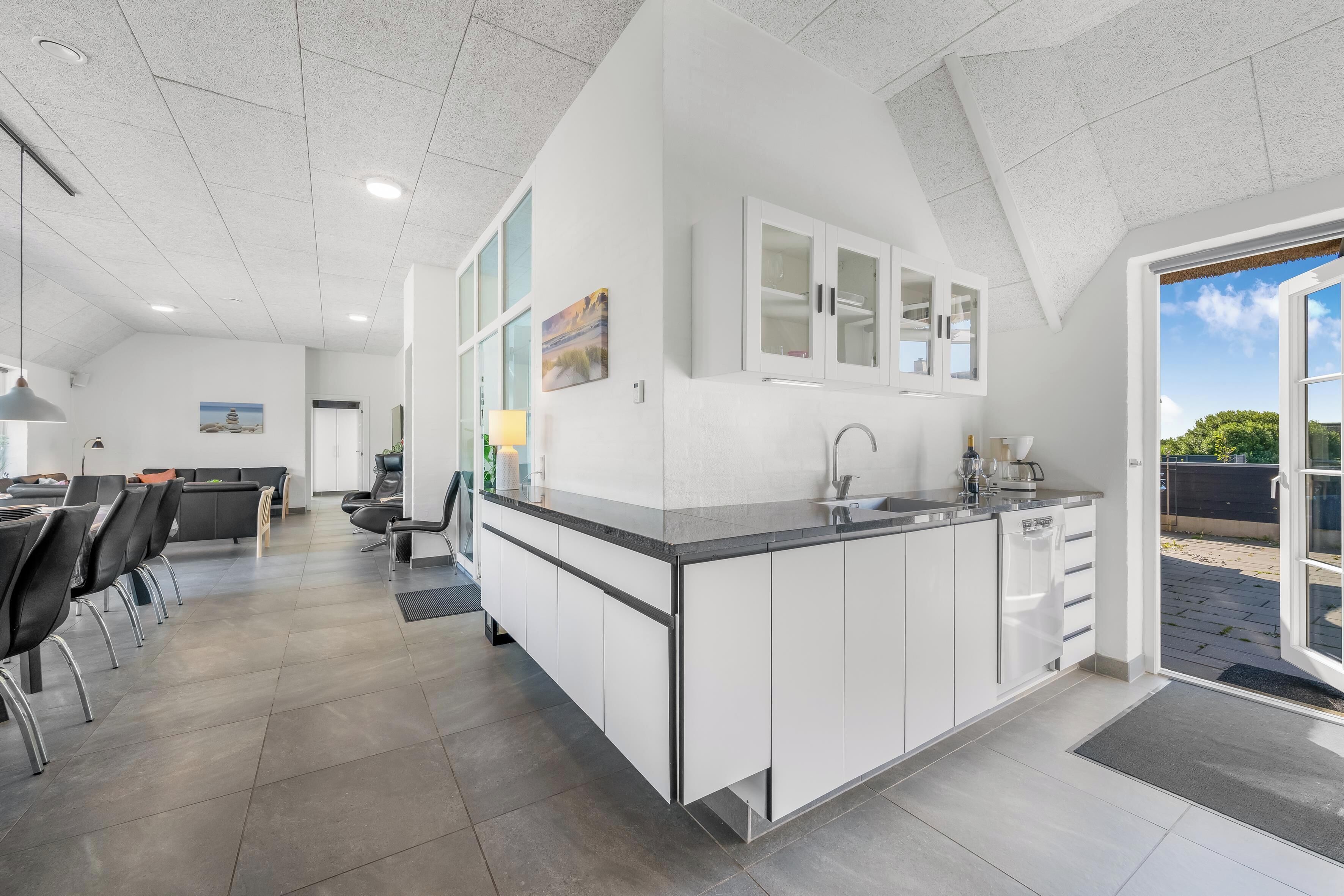 Una cocina moderna con armarios blancos, una isla integrada y un amplio ventanal con vistas al exterior.