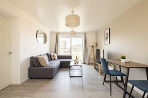 A modern living room with a grey sofa, a coffee table, and a TV stand. - 2 Bedrooms Apartment in Wembley (Wembley)