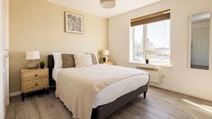 A bedroom with a bed, bedside tables, a window with a view, and a ceiling light. - 2 Bedrooms Apartment in Wembley (Wembley)