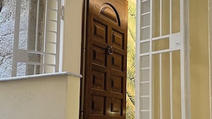 A wooden door with a metal gate, leading to a staircase with marble steps. - Suite Duomo Tropea (Tropea)