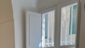 A corner room with a window overlooking a building with green shutters. - Suite Duomo Tropea (Tropea)