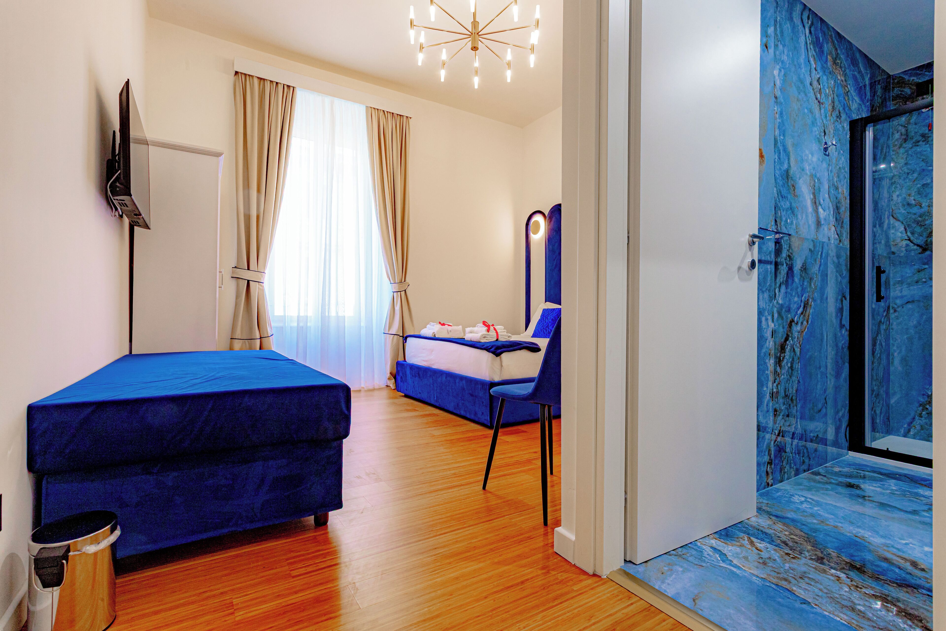 A room with a bed, a chair, a mirror, and a shower area.