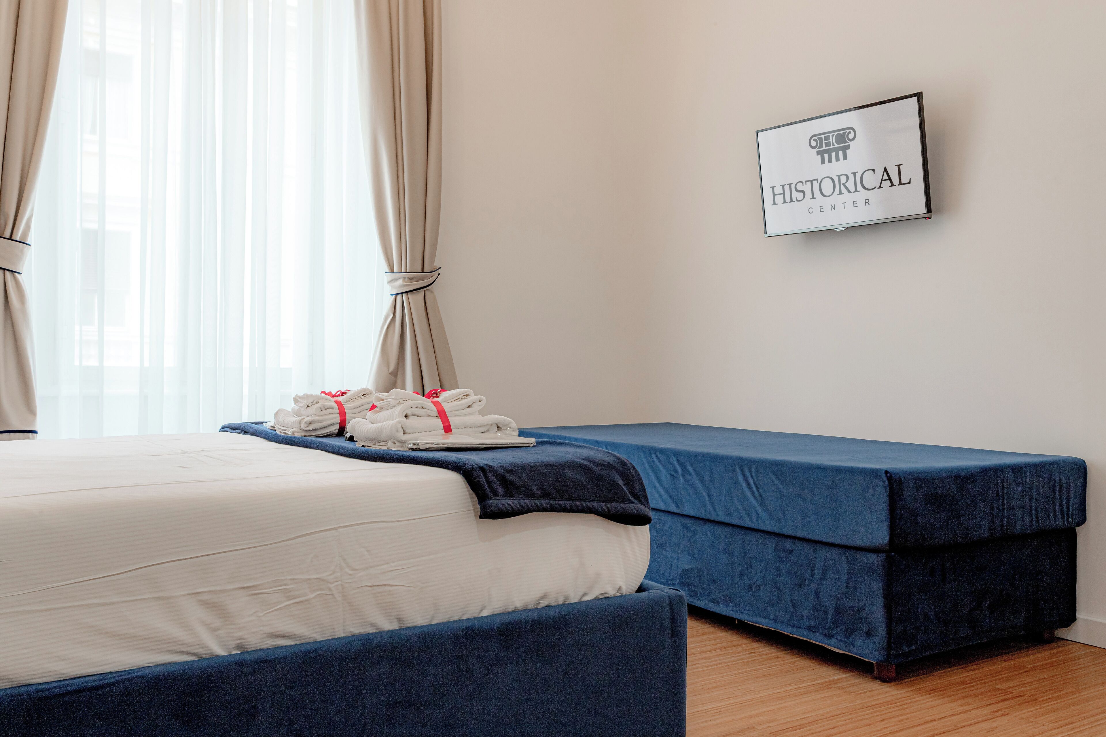 A hotel room with a bed, a blue sofa, and a framed sign on the wall.