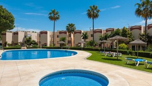 Une piscine avec des chaises longues et des palmiers.