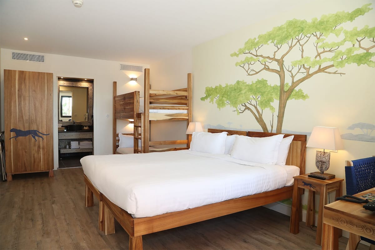 Une chambre à coucher avec un grand lit, une tête de lit en bois, une table de chevet avec une lampe, une armoire en bois et un miroir.
