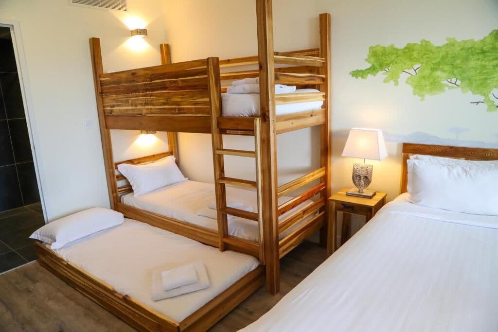 Une chambre avec un lit superposé, une échelle en bois, une table de chevet avec une lampe et une fresque murale.