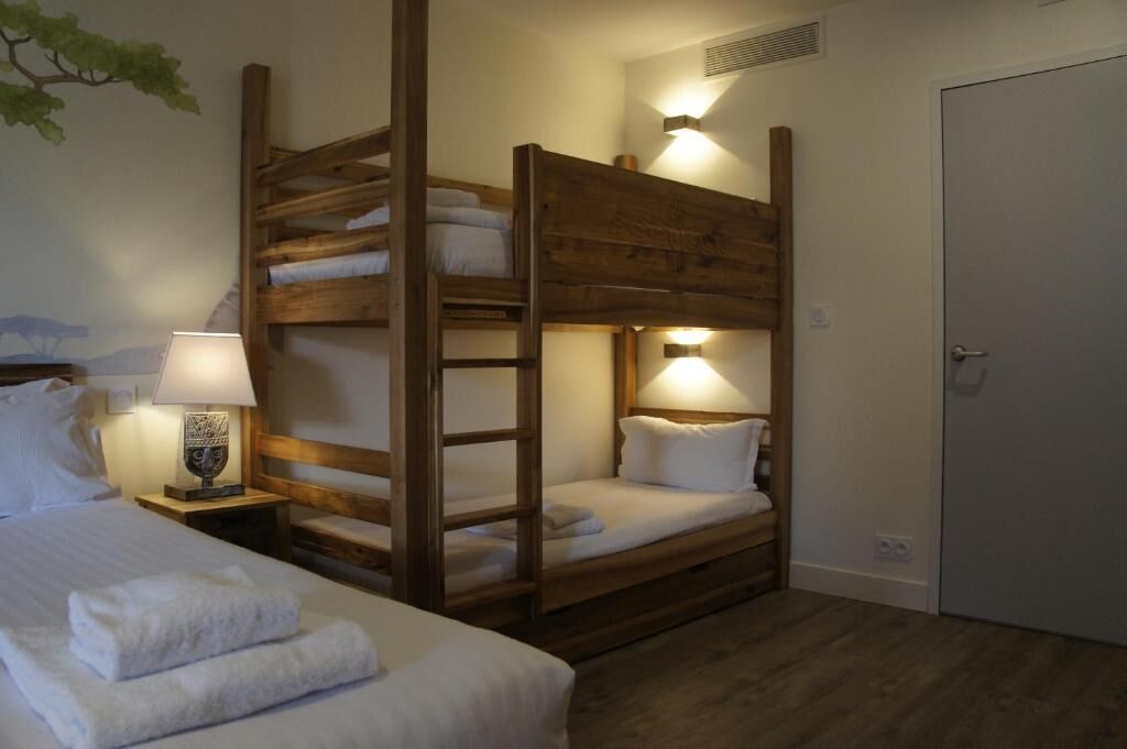 Dormitorio con literas y dos mesitas de noche, cada una con una lámpara.