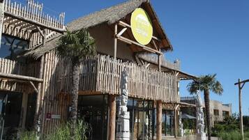 A building with a thatched roof and wooden structure, featuring a sign that reads "The Baths of Beaulieu."