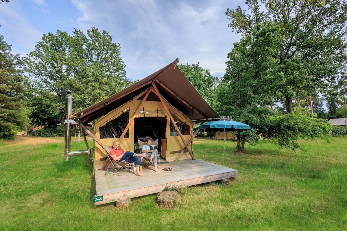A small, rustic wooden structure with a pitched roof, a porch, and a metal chimney.