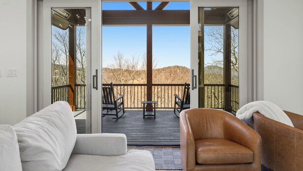 A room with a sliding glass door leading to an outdoor deck with a view of a hilly landscape. - Modern Mountain Lodge with Great Amenities (Boone)