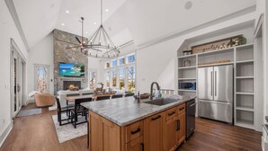 A spacious kitchen with a large island, wooden cabinets, and a stainless steel refrigerator. - Modern Mountain Lodge with Great Amenities (Boone)
