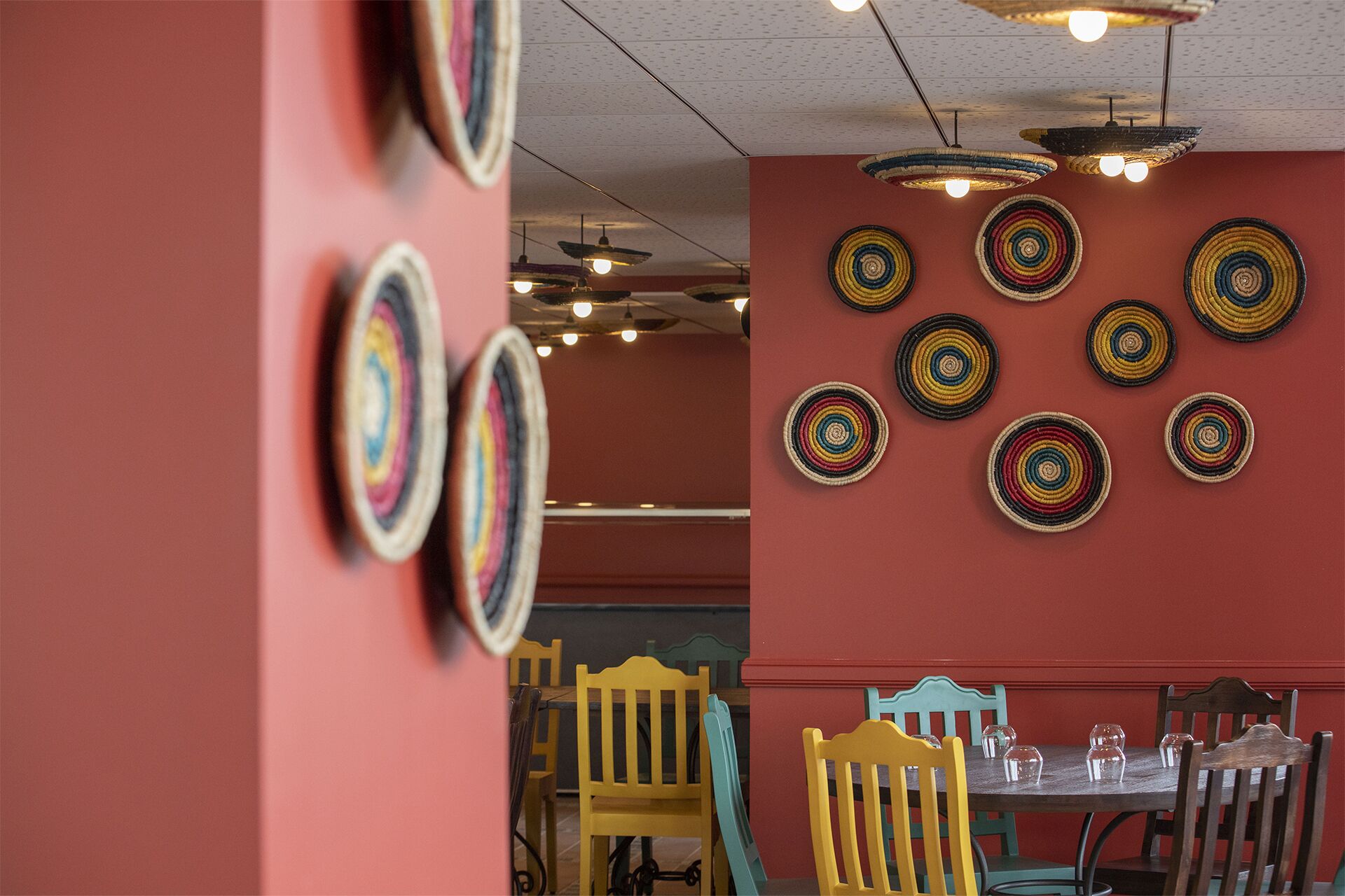 Un comedor con pared roja, una mesa dispuesta con sillas y adornos circulares en la pared.