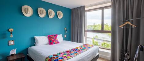 A hotel room with a large bed, a view of the outdoors, and a window with curtains.