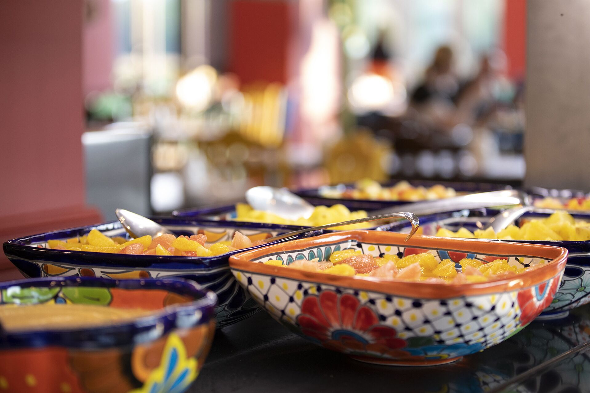 A buffet with various dishes in colorful bowls.