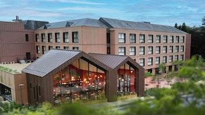 A modern building with a restaurant on the ground floor, featuring large windows and a patio area. - Les Rivages de Beauval (Saint-Aignan)