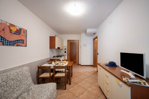 A compact living space with a kitchenette, dining area, and a television on a wooden cabinet.