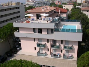 A modern building with a rooftop pool and outdoor seating area.