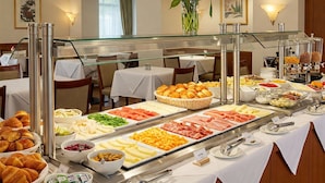 Buffet variado com carnes, queijos e doces, em um hotel.