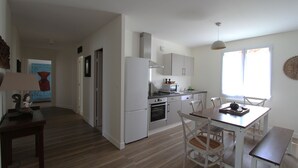 Una cocina moderna con electrodomésticos blancos, un comedor con mesa y sillas, y un ventanal que aporta luz natural.