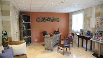 A spacious living area with a wooden coffee table, a bookshelf, a desk with a computer, and a window providing natural light.