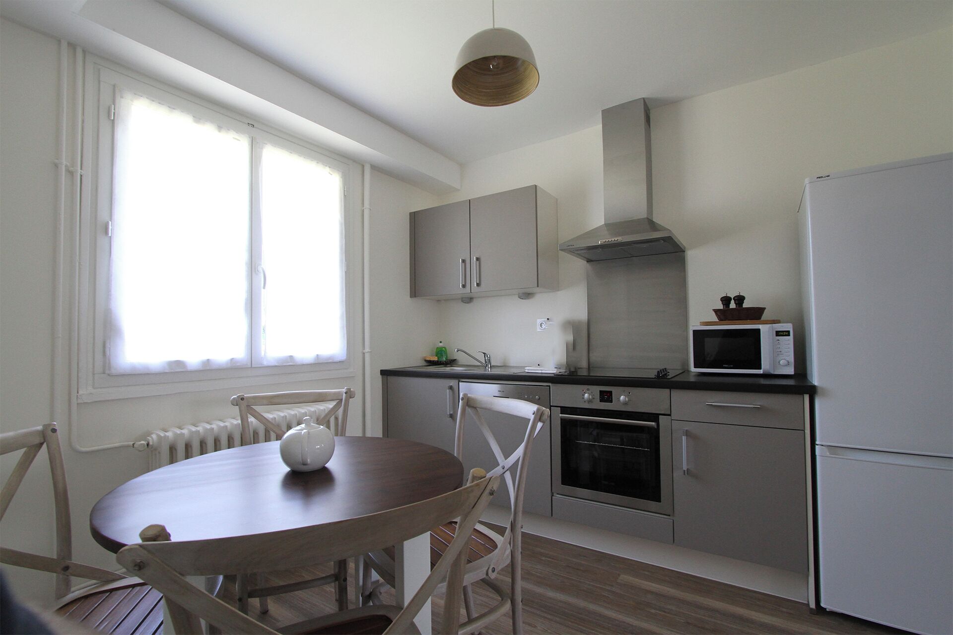 Cocina compacta con comedor, que incluye horno integrado, microondas y campana extractora de acero inoxidable.