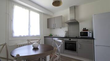 Cocina compacta con comedor, que incluye horno integrado, microondas y campana extractora de acero inoxidable.