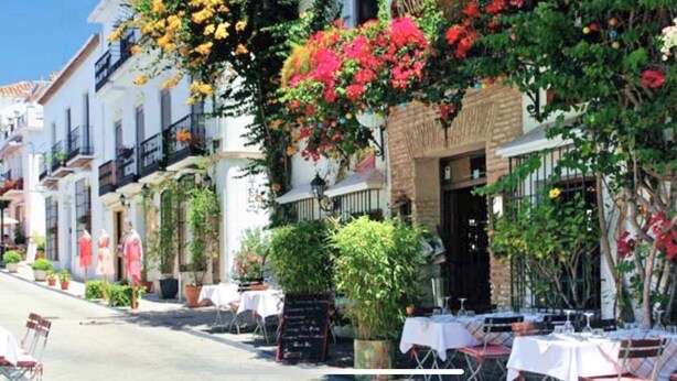 Une rue bordée d’immeubles, dont certains sont dotés de balcons et de terrasses.