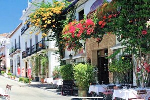 Une rue bordée d’immeubles, dont certains sont dotés de balcons et de terrasses.