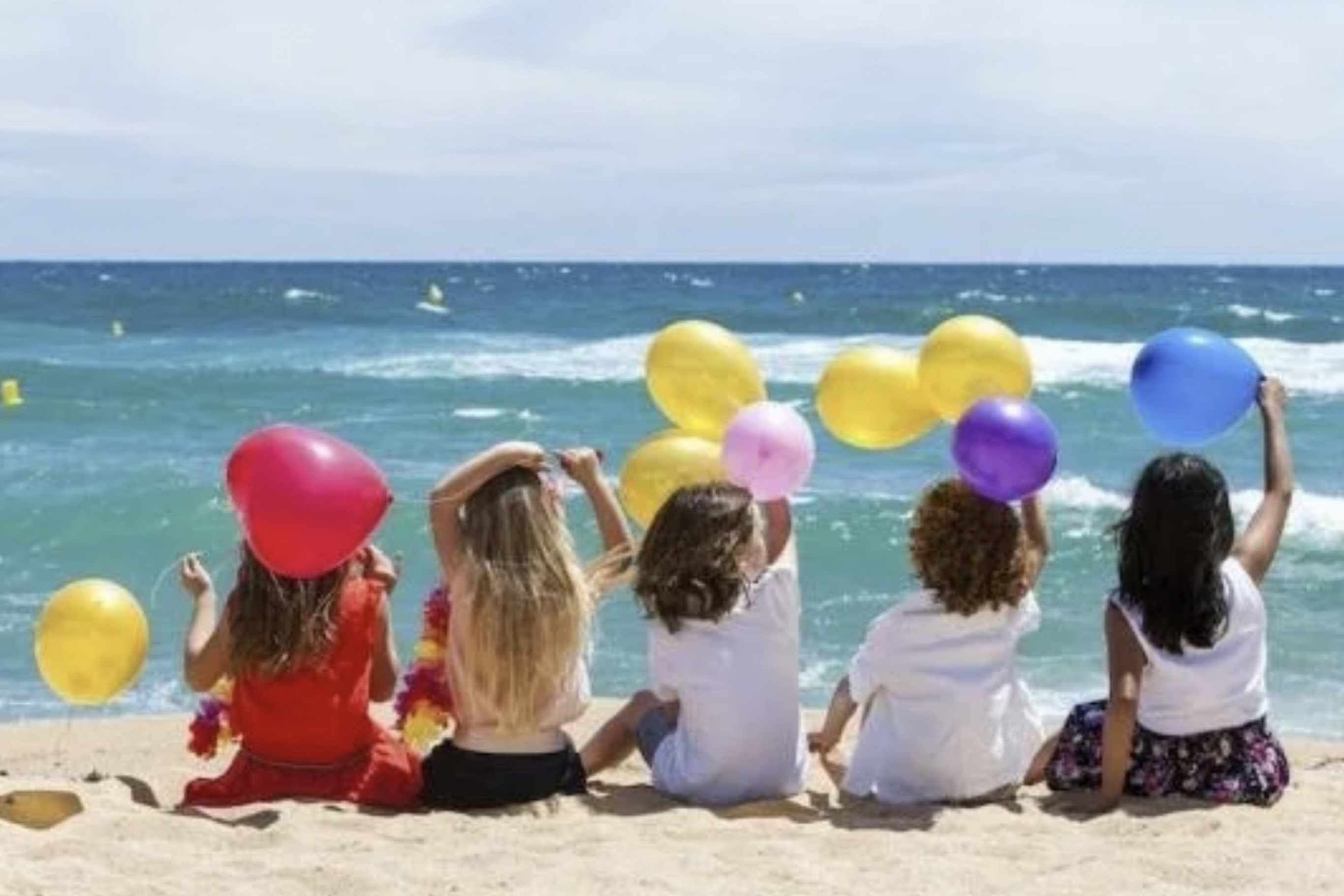 A group of people sitting on a beach with the ocean in the background.