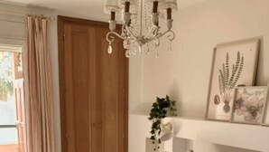 A bedroom with a large bed, a chandelier, a wooden door, and a window with curtains.