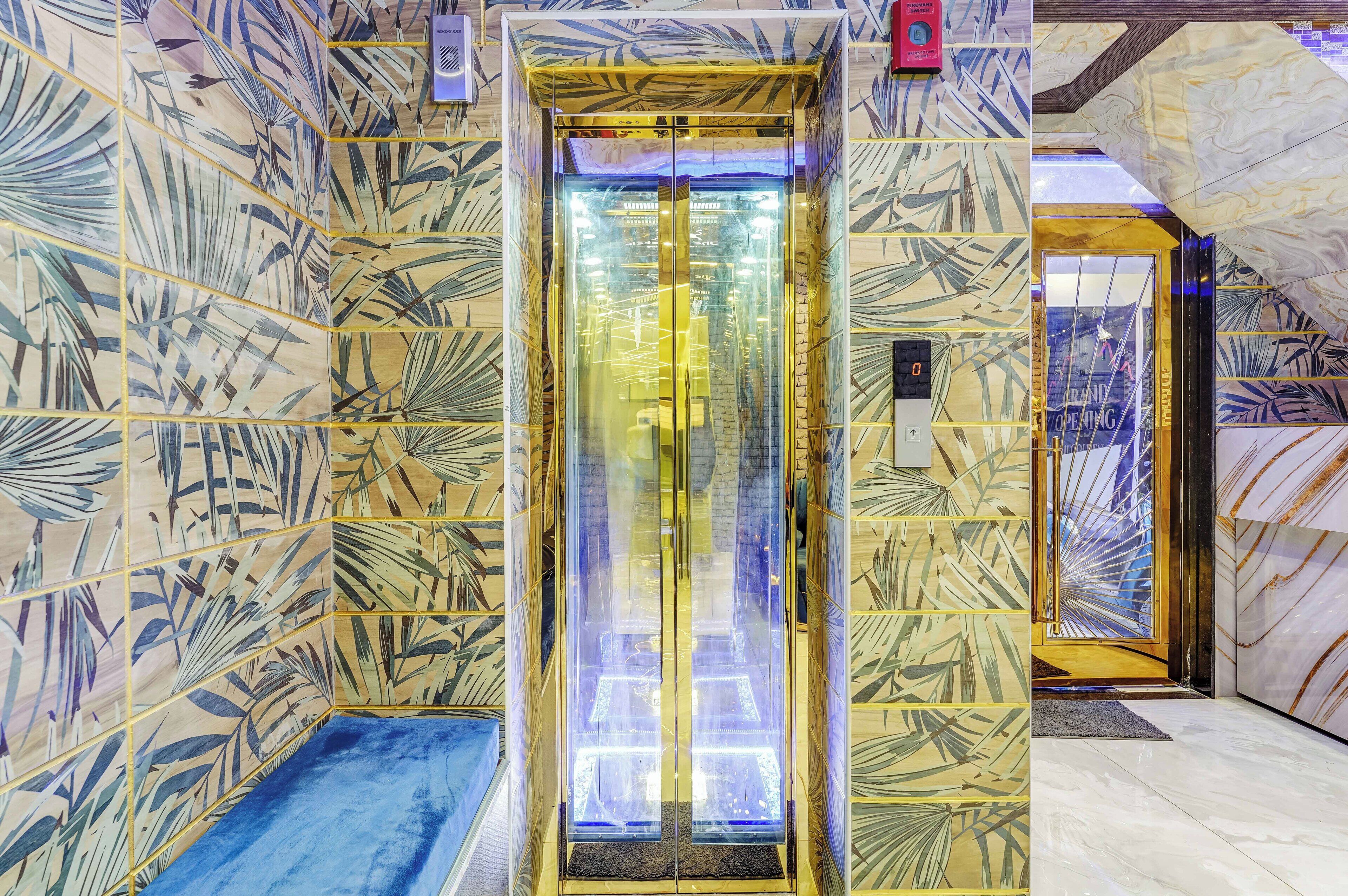 Un ascenseur doté de portes en verre, entouré de murs décorés de motifs.