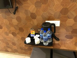 A coffee station with a coffee maker, cups, a box of Nespresso capsules, and several Aquafina water bottles on a tray. - The K11 Golden Gate (Chennai)