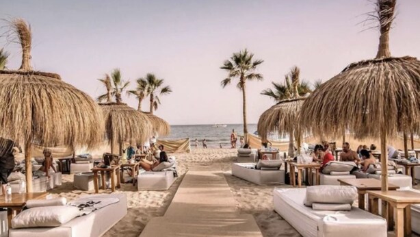 A beachside lounge area with thatched umbrellas, lounge chairs, and a sandy walkway leading to the sea. - Marbella - Beachside One bedroom apartment (Marbella)