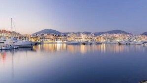 A marina with yachts docked, a coastal town with buildings, and a mountain in the background. - Marbella - Beachside One bedroom apartment (Marbella)