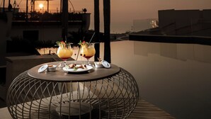 Una mesa con bebidas y platos, palmeras y un edificio al fondo.